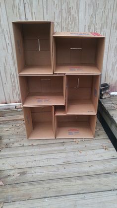 four cardboard boxes stacked on top of each other in front of a wooden wall and floor