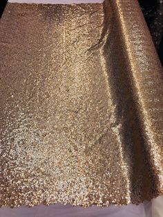 a gold sequin table cloth on top of a white tablecloth covered in glitter