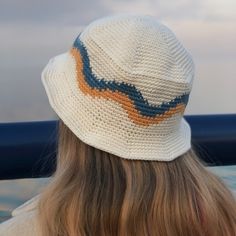 the back of a woman's head wearing a white hat with blue, orange and yellow stripes