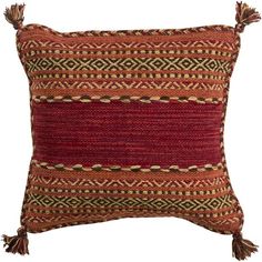 a red and brown pillow with tassels on the sides, sitting against a white background