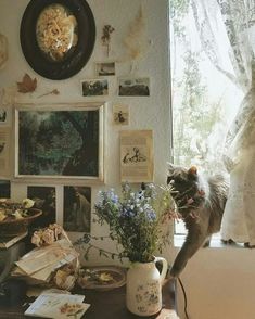 a cat standing on top of a table next to a vase filled with flowers