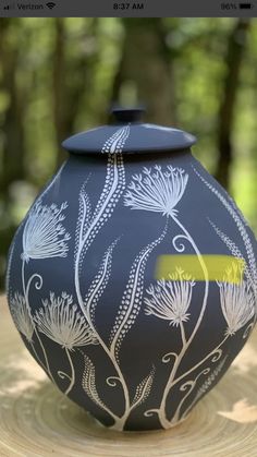 a blue vase sitting on top of a wooden table next to trees in the background