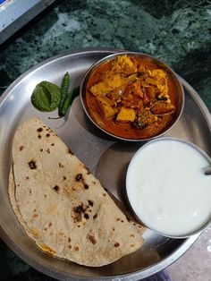 a metal plate topped with food next to a bowl of milk