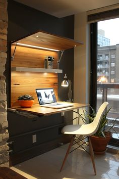 a laptop computer sitting on top of a wooden desk next to a plant in a pot