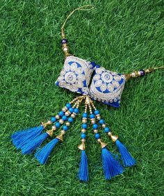 a blue and white beaded necklace with tassels on it sitting in the grass