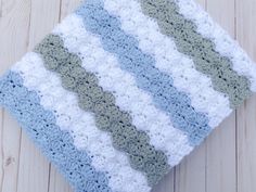 a blue and white crocheted blanket laying on top of a wooden floor