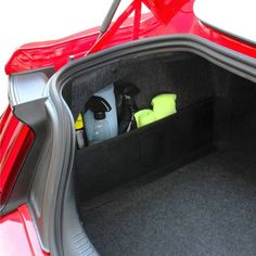 the back end of a red car with its trunk open and various items in it