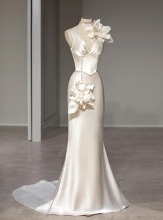 a white wedding dress with flowers on the front and back, is displayed in an empty room