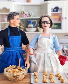 two dolls standing next to each other in front of food