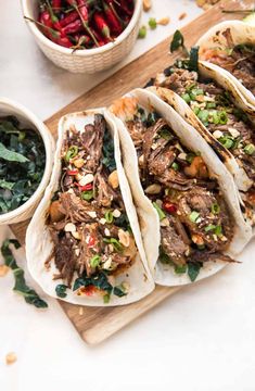 several tacos with meat and vegetables on a cutting board