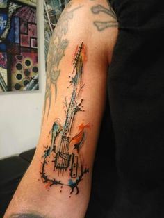 a man's arm with a guitar tattoo on the left side of his arm