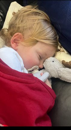 a small child sleeping with a stuffed animal