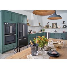 a kitchen with green cabinets and an island in front of the stove top ovens