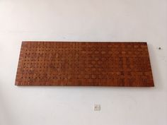 a wooden wall hanging on the side of a white wall