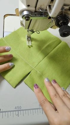 someone is using a sewing machine to sew on some green fabric with their hands