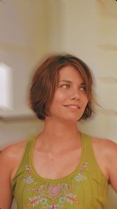 a woman in a green tank top is posing for the camera