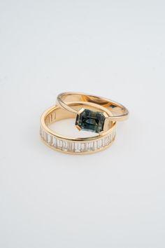 two gold rings with an emerald and baguette cut diamond set in the middle