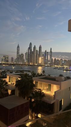 the city skyline is lit up at night, with palm trees and buildings in the foreground