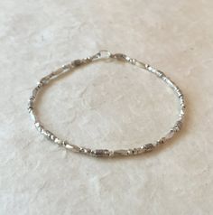 a silver beaded bracelet sitting on top of a table