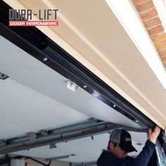 a man is working on the underside of a garage door with an overhead track bar