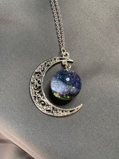 The Grogerous galaxy which hand poured with high quality UV resin.  The necklace come with a moon chain and a sparkling galaxy.  The scene may be changed depending on the light, and your angle of view.  You may choose black or blue galaxy if you like. The pendant is around 4cm across (the galaxy ball is 2cm) and comes on 44cm rhodium plating silver chain.  This material is more shining, sparkling and longlasting than the sterling silver. We use the materials from Japan and South Korea.  Packagin Space-themed Black Jewelry Gift, Silver Resin Necklaces For Parties, Adjustable Celestial Necklace For Party, Adjustable Celestial Style Party Necklaces, Magical Silver Resin Jewelry, Silver Resin Jewelry With Magical Style, Moon Chain, Galaxy Jewelry, Galaxy Necklace