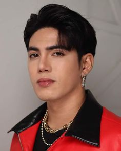 a close up of a person wearing a red leather jacket and pearls on his necklace