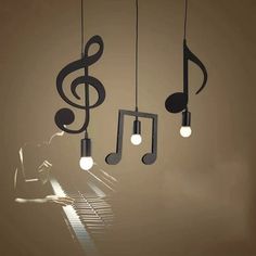 three musical notes hanging from the ceiling above a piano keyboard and light bulb chandelier