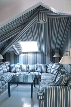 a living room filled with blue and white striped couches next to a lamp on top of a table