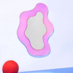 an apple sitting in front of a mirror on a wall next to a red ball