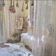 a room filled with lots of white curtains and flowers on the window sills