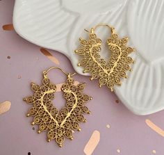 These filigree earrings are crafted from sterling silver with a lavish 24k gold plating, exuding opulence. Featuring a heart design interwoven with floral accents, each pair is a statement of elegance and a homage to the art of filigree. Ideal for enhancing any ensemble, they speak of a love for beauty and meticulous attention to every link and curve. Perfect for the chic individual seeking an accessory with history and artistry. Thanks Gold Hoop Earrings With Intricate Design For Gift, Luxury Gold Heart Earrings For Wedding, Ornate Gold Hoop Earrings For Gift, Elegant Gold Handmade Heart Earrings, Ornate Gold Jewelry For Valentine's Day, Gold Brass Heart Earrings, Gold Brass Heart Earrings Pierced, Gold Brass Heart Earrings With Pierced Details, Gold Heart Earrings In Brass