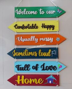 colorful wooden signs hanging on a wall with the words welcome to our comfortable happy usually messy sometimes loud full of love home