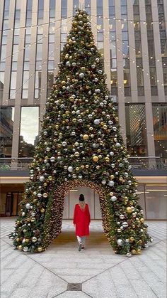 a woman standing in front of a christmas tree