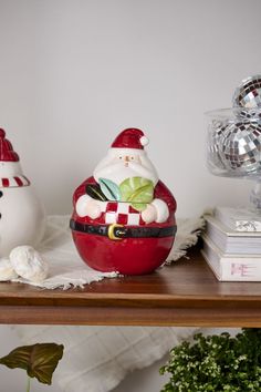 a santa clause figurine sitting on top of a table next to other christmas decorations