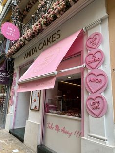 a store front with pink and white decorations on the outside, including hearts hanging from the roof