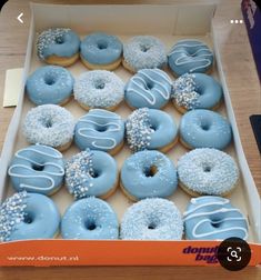 a box filled with blue frosted donuts covered in sprinkles on top of a wooden table