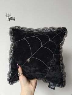 a person holding up a black pillow with spider webs on the front and sides