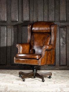 an old leather office chair sitting in front of a wooden wall