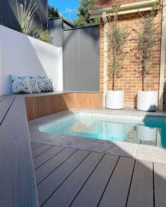 an empty swimming pool in the middle of a wooden decked area with potted plants