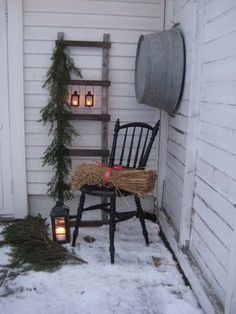 a rocking chair sitting on top of a snow covered ground next to a ladder with candles