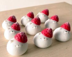 small white rocks with red hats on them sitting on a wooden counter top in the shape of snowmen