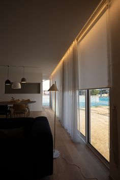 a living room filled with furniture next to a window covered in white drapes and lights