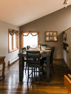 a dining room table and chairs in front of a window with wooden flooring next to a piano