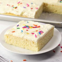 a piece of cake with white frosting and sprinkles on a plate