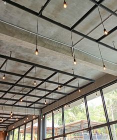 an empty restaurant with large windows and lots of light bulbs hanging from it's ceiling