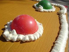 two red and green balls sitting on top of a table covered in white icing