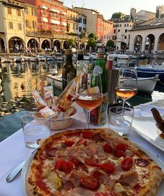 a pizza sitting on top of a white plate next to a table filled with glasses of wine