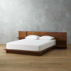 a bed with white pillows and wooden headboard in a room that has wood flooring