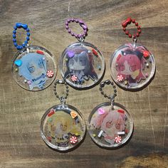 four keychains with cartoon characters on them sitting on top of a wooden table