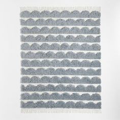 a gray and white rug with fringes on it's edges, in the shape of waves